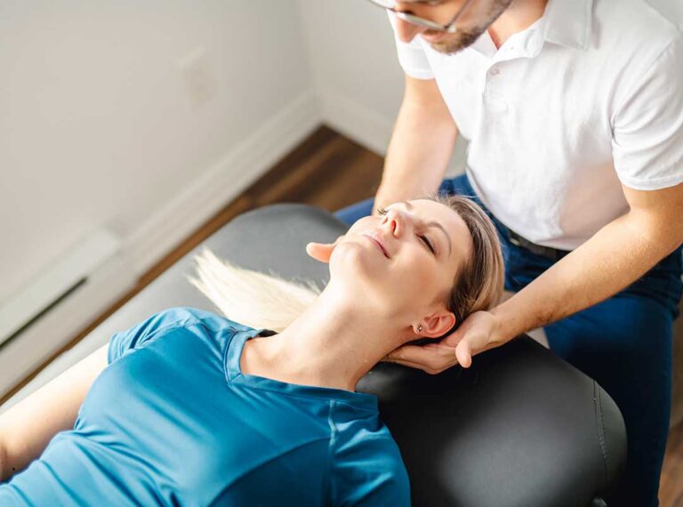 A person stretches their back gently in a bright, comfortable home living room, suggesting mild muscle soreness.